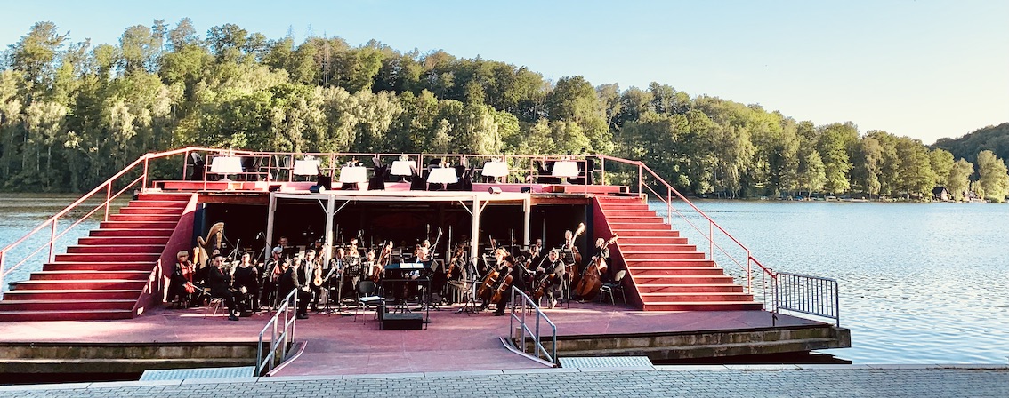 Seebühne Kriebstein. Das Orchester probt noch, oben warten weiß eingedeckte Tische auf das Ensemble des Musiktheaters.