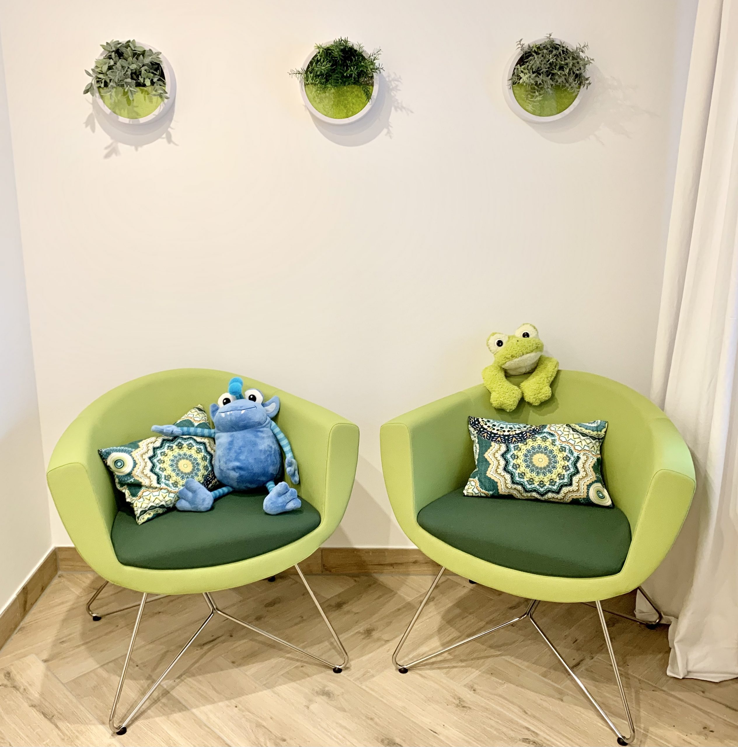 Zwei Plüschtiere sitzen auf grünen Sesseln.